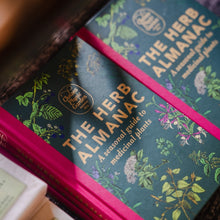 Load image into Gallery viewer, Two copies of The Herb Almanac book displayed in The Real Mary King's Close gift shop