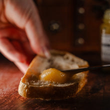 Load image into Gallery viewer, Lemon curd being spread on a slice of bread
