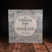Load image into Gallery viewer, The Colouring Book of Scotland displayed on a wood panelled desk