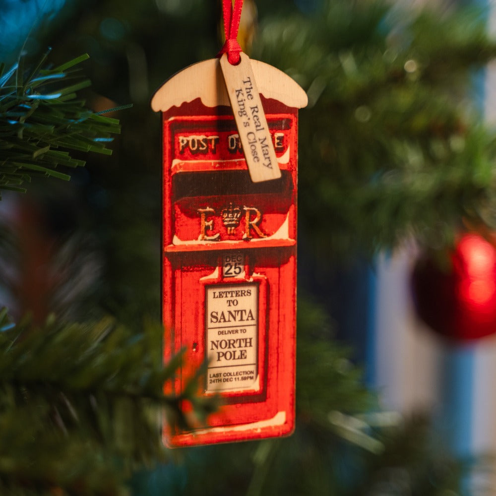 Wooden post box decoration hanging on a Christmas tree, labelled with a message reading 
