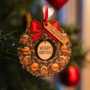 A wooden wreath decoration hanging on a tree that says "Merry Christmas" and The Real Mary King's Close label