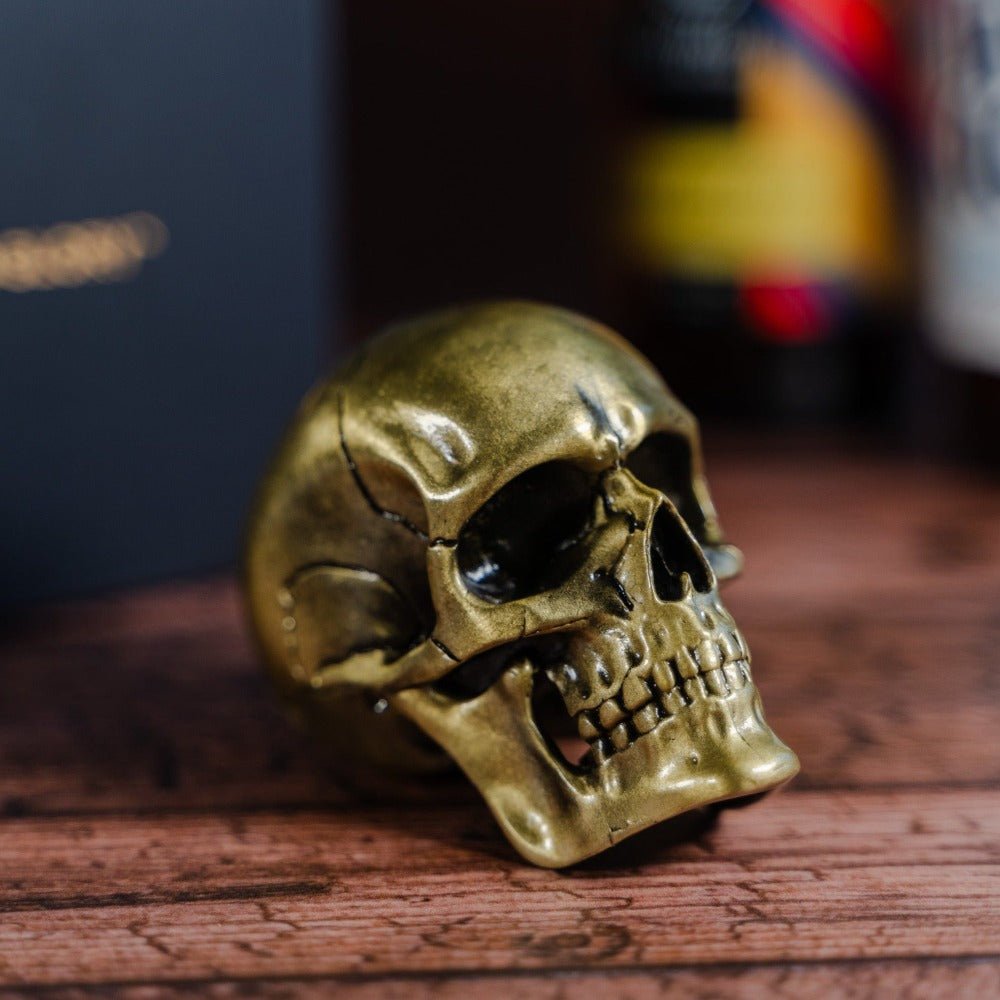 small gold skull bottle opener on a wooden table