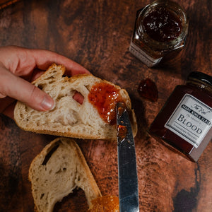 Strawberry jam being spread on a slice of bread 