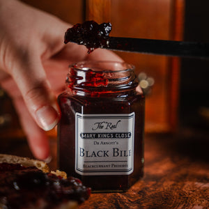 Blackcurrant preserve being scooped out of a jar labelled "black bile"