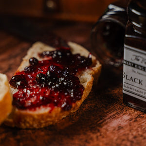 Blackcurrant preserve being spread on a slice of bread