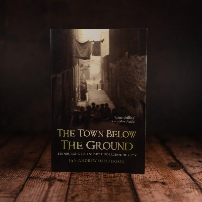 The Town Below the Ground front cover displayed on a wooden-slatted table
