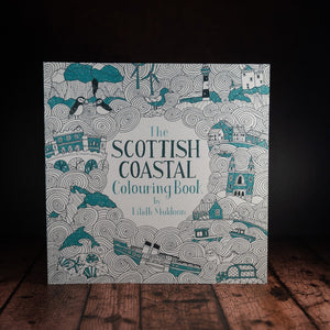 The Scottish Coastal Colouring Book displayed on a wood panelled desk