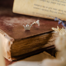 Load image into Gallery viewer, Simple three-pronged silver crown earrings displayed on a weathered book
