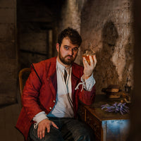 Man in red 17th century coat holding a circular jug of urine on mary king's close 