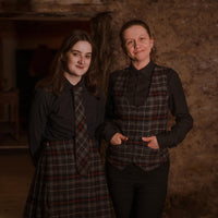 Girl wearing a Kinloch Anderson tartan tie and kilt beside a woman in tartan waistcoat. 