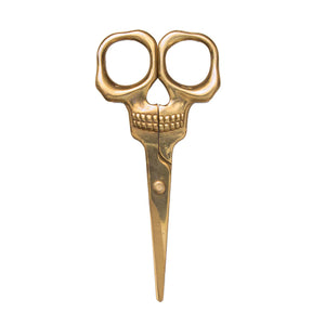 Golden skull scissors against a white background